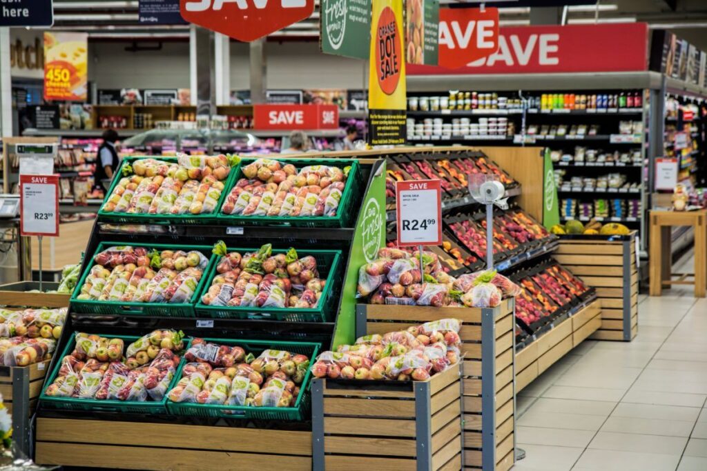 A imagem se trata de uma foto de gondolas de mercado cheia de frutas. A foto representa a recuperação de créditos tributários para supermercados, o tema deste artigo.